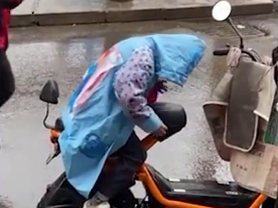 孩子用身体给妈妈电动车座位挡雨